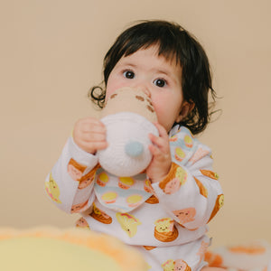 cute baby wearing the wee bean dim sum long sleeve onesie and biting on boba doll