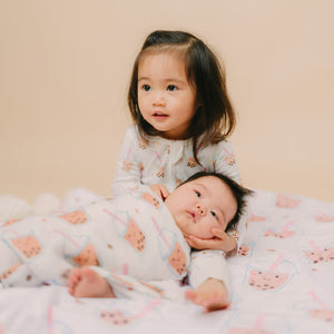 cute girl hugging baby swaddled in boba pajamas