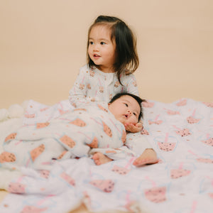 older sister holding baby sister swaddled in boba blanket